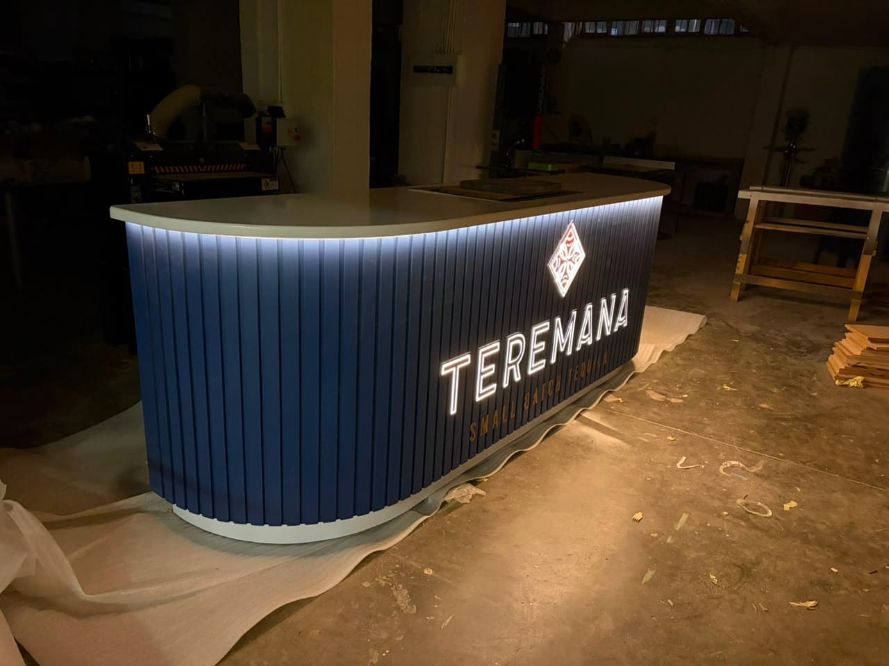 The finished Teremana counter fully lit in a dark workshop, backlit lettering glowing